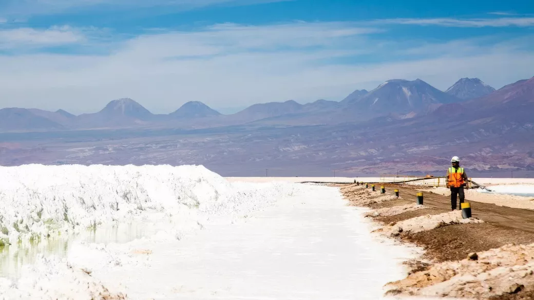 Worker on a barrier in the Salar with piles of lithium salts. 