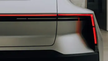 Close-up of the rear end of a modern car, displaying a sleek tail light design integrated into the trunk, with a focus on the car's smooth gray paint and sharp body lines.