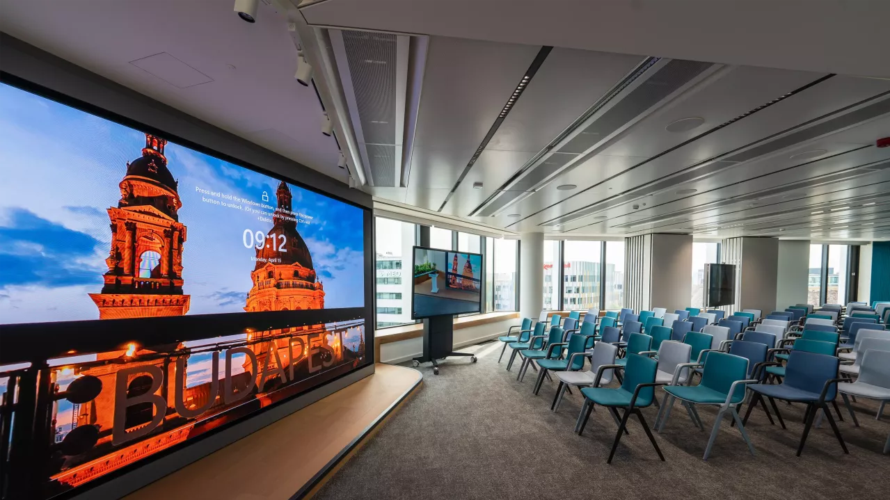 Conference room with large screen and many chairs. 