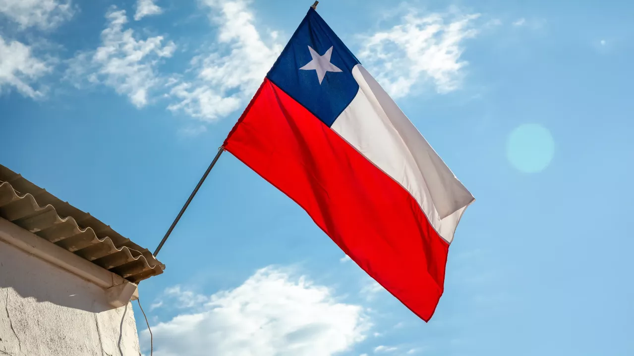 Chile National Flag waving on pole against sunny blue sky.