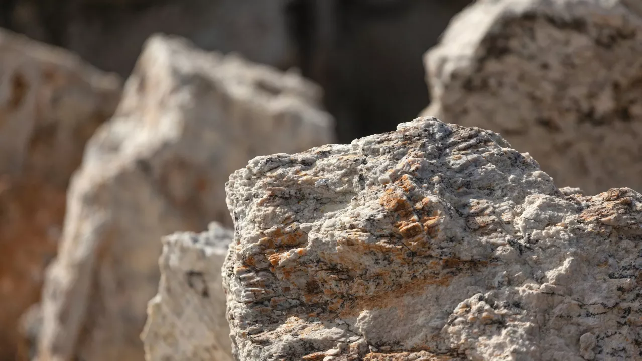 Close-up of rough, textured limestone rocks with sharp edges and varied color tones, highlighted by natural sunlight.