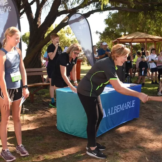 Community event with several young woman and Albemarle representative shaking hands with winner of race.