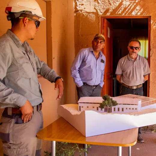 Leader and community representatives gathered around an architectural model of a site.